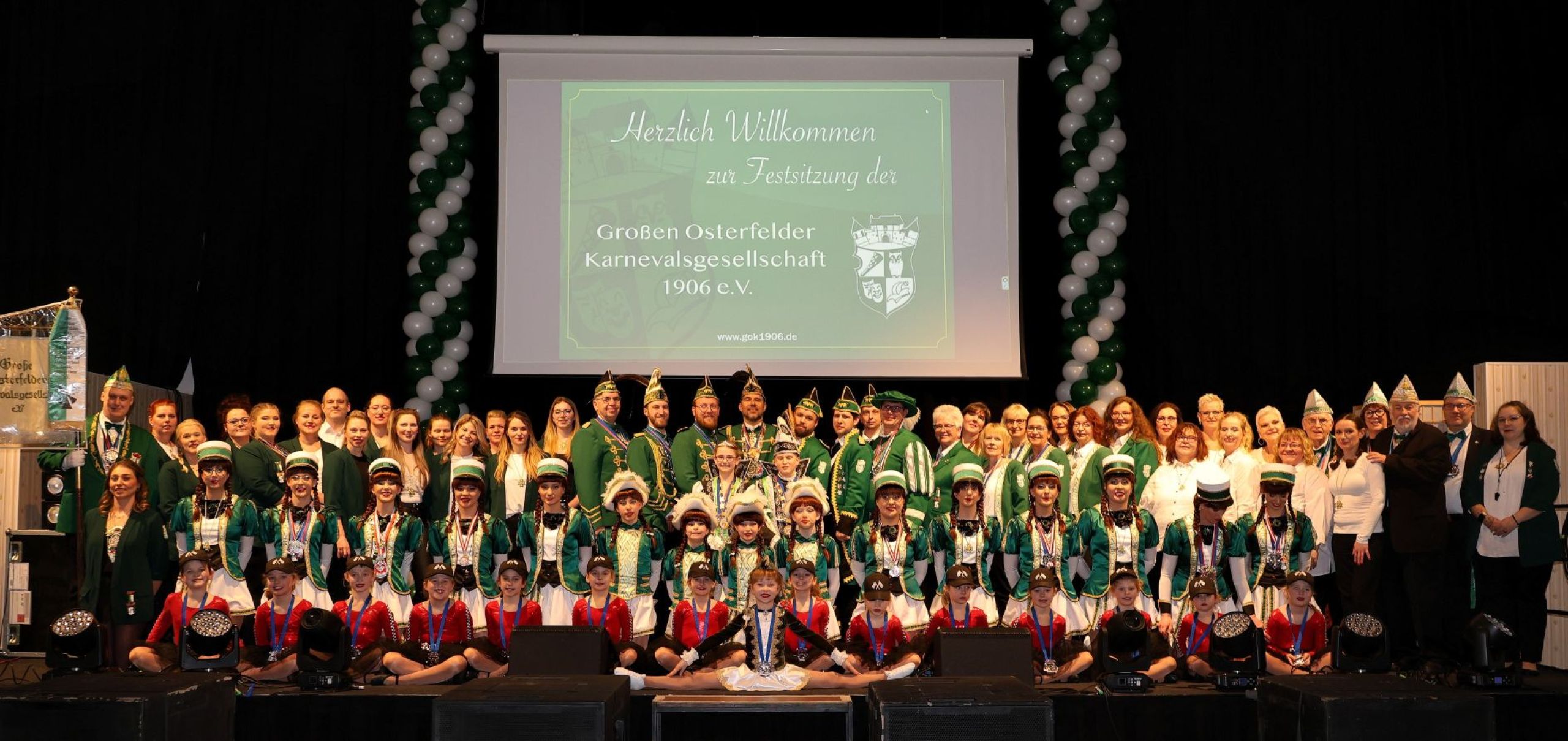 Gruppenfoto der Großen Osterfelder Karnevalsgesellschaft 1906 e.V. mit allen Garden und Aktiven vor bergbauhistorischem Bühnenbild.